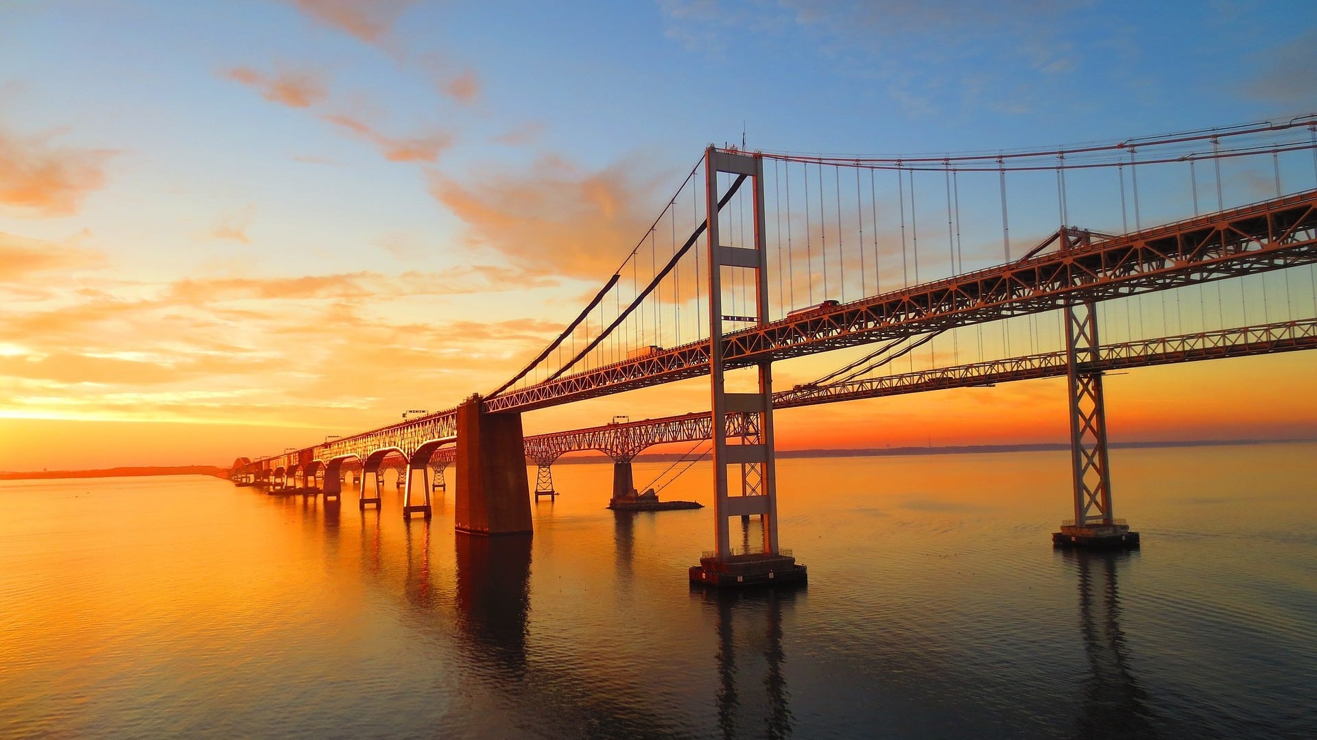 An expansive suspension bridge over a large body of water at sunset